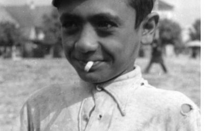 Boy with hat, torn shirt and cigarette butt in the mouth