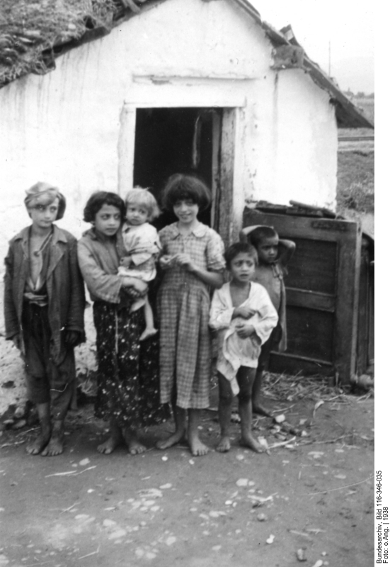 Children with torn clothes in front of a house