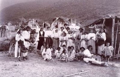 Group of Gypsies (men, women, children) in front of cottages